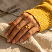 Gold vermeil cushion-cut citrine ring worn on a hand against neutral linen