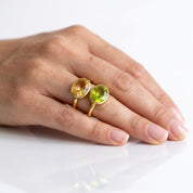 Model wearing citrine and peridot birthstone ring on hand against white background