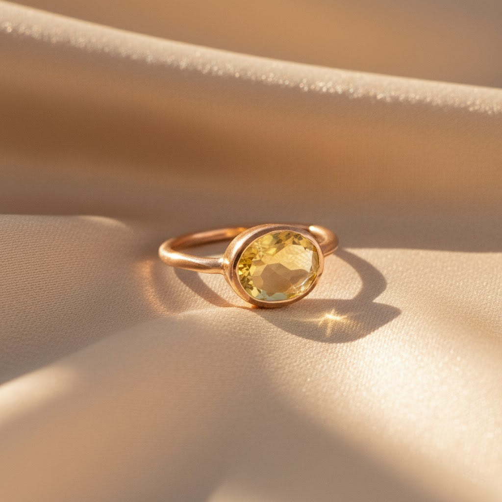 Close-up of oval faceted citrine ring in 18K rose gold vermeil, yellow gemstone capturing sunlight on satin background, handcrafted November birthstone jewelry gift for women.
