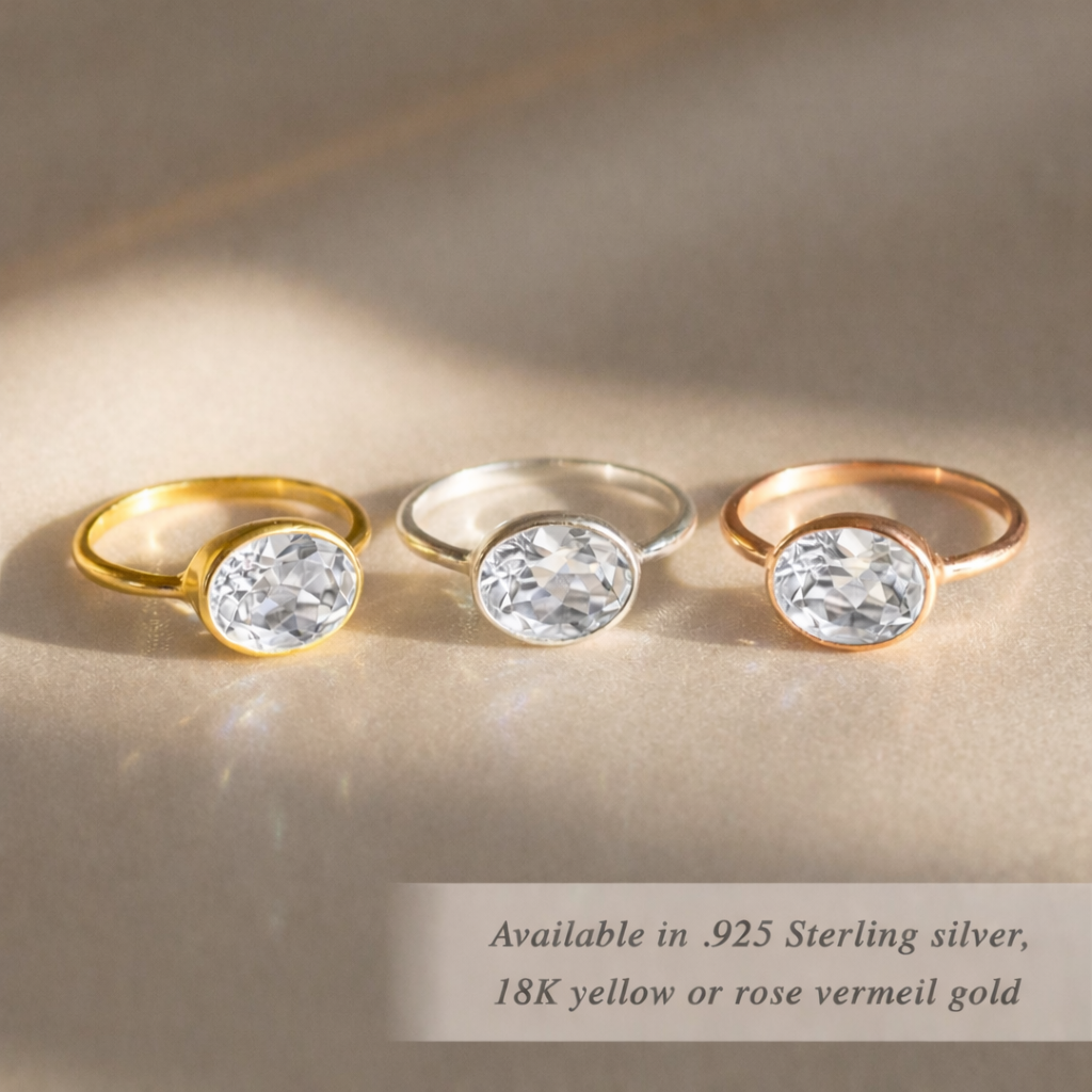Oval clear quartz ring with gold and silver gemstone rings on satin background, mix and match birthstone ring collection