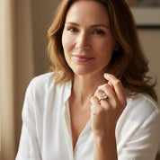 Close-up portrait of woman wearing cushion cut clear quartz ring in polished gold bezel setting, April birthstone diamond alternative jewelry, square transparent gemstone glowing softly, minimalist fine jewelry, dainty stacking birthstone ring, handcrafted artisan gold quartz statement ring