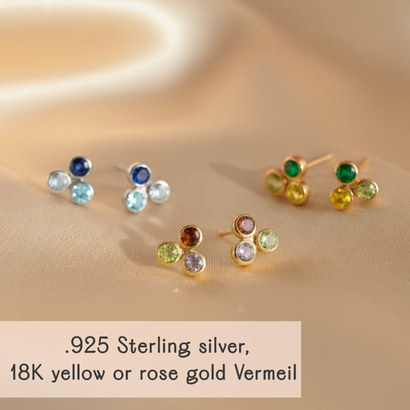 Cluster birthstone bar stud earrings arranged on soft satin fabric, available in .925 sterling silver, 18k yellow gold vermeil, or rose gold vermeil. Dainty bezel-set gemstones represent all twelve birthstones, perfect for birthday gifts, bridesmaid jewelry, or personalized mom earrings. Minimalist multi-stone studs with vibrant, meaningful gemstone accents for everyday elegance.