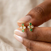 Tiny four birthstone cluster earrings held between fingers to show the petite scale and colorful natural gemstones
