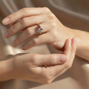 dainty three stone birthstone ring shown stacked with minimalist bands on woman’s hand, personalized gemstones representing her children in vibrant colors, gold vermeil band offering elegant modern style, customizable family ring perfect for Mother’s Day or birthday gifting, crafted in sterling silver or gold vermeil with high-quality stones, sentimental jewelry piece for moms who cherish family connections