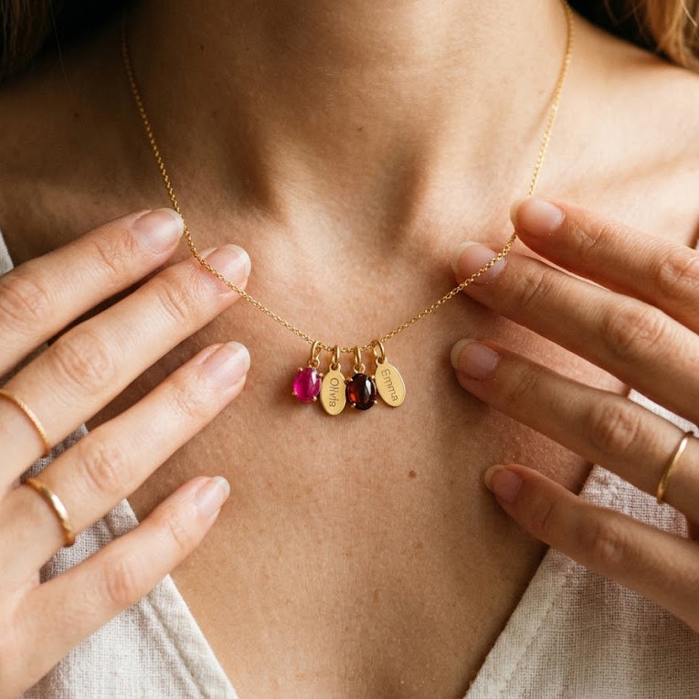 Woman wearing a custom family birthstone necklace with engraved children's names in yellow gold.
