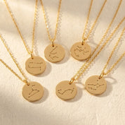 Collection of personalized zodiac constellation necklaces with round engraved disc pendants in warm natural light.