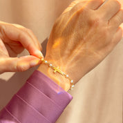 Gold cross bracelet with freshwater pearls shown on wrist, elegant religious jewelry gift for women. Perfect for baptism, confirmation, first communion, or christening. A meaningful keepsake for daughter, goddaughter, granddaughter, mom, or best friend. Thoughtful Catholic gift for birthdays, Christmas, Easter, or religious milestones. Dainty faith bracelet blends modern fashion with timeless spiritual symbolism, ideal for everyday wear or special occasions.