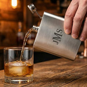 Engraved stainless steel flask pouring a drink into a glass, showcasing precision laser engraving and sleek brushed finish, personalized flask gift for men who appreciate quality barware, custom engraved hip flask perfect for groomsmen, weddings, or anniversaries, durable stainless steel flask designed for everyday use and special occasions