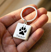Custom pet paw print keychain engraved with dog name, shown held in hand to highlight detailed paw engraving and polished stainless steel finish. This personalized paw print keychain makes a meaningful dog memorial gift, sympathy gift for pet loss, or everyday keepsake for dog lovers. Ideal for dog moms, pet owners, and anyone wanting a custom pet accessory that honors a beloved companion with lasting quality and sentimental value.