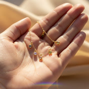 Close detail of birthstone charm necklace in hand — tiny custom gemstone’s birthstone necklace for mom gift