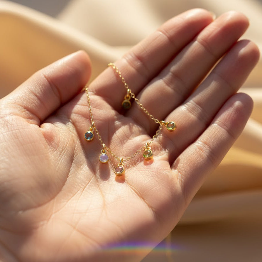 Close detail of birthstone charm necklace in hand — tiny custom gemstone’s birthstone necklace for mom gift