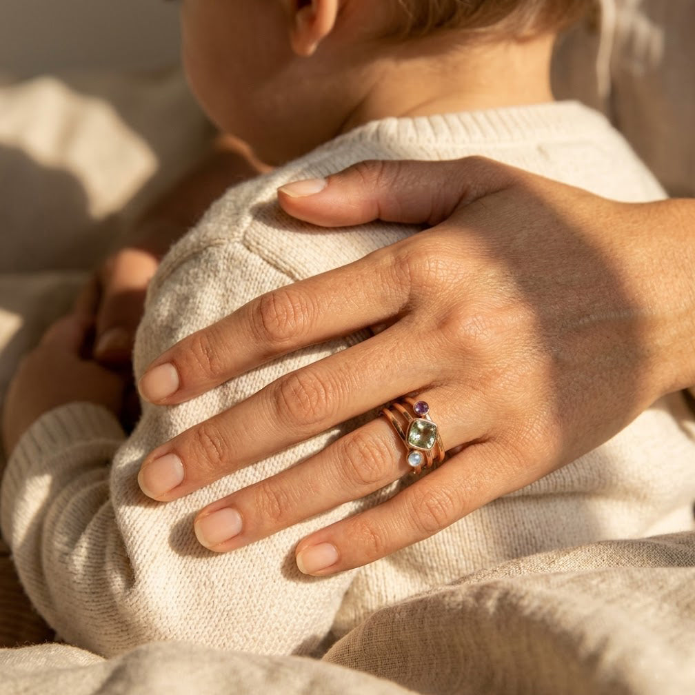 Mom wearing a personalized birthstone ring while holding baby, a sentimental family jewelry gift for new moms and Mother’s Day.