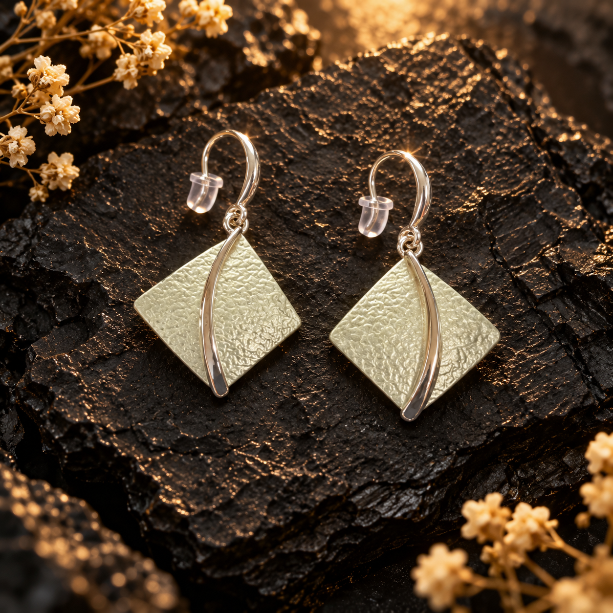Soft Pearl sculpted leaf drop earrings with curved metallic center detail on dark stone
