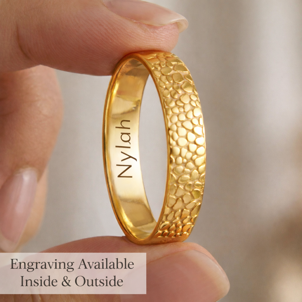 Close up of a gold pet nose print ring held between fingers showing optional inside engraving with a name or short message, paired with an outside nose texture engraving created from your dog’s real nose photo, a meaningful custom memorial ring for pet loss and remembrance, ideal rainbow bridge gift for dog moms, sleek polished band with durable laser engraved detail and a smooth comfort interior that feels easy for everyday wear.