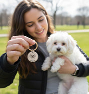 Woman holding a small dog while showing a personalized pet portrait keychain. Custom engraved pet keychain created from a photo, featuring a detailed dog illustration. Meaningful pet keepsake gift for dog moms, pet parents, or memorial jewelry honoring a beloved companion.