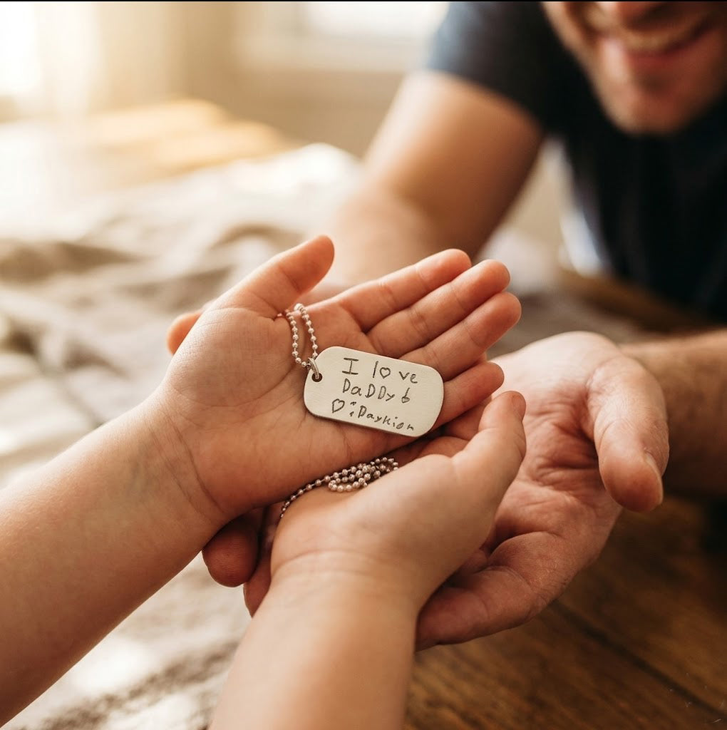 Father wearing engraved dog tag necklace with child hugging him