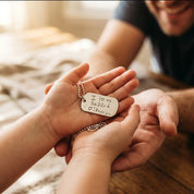 Father wearing engraved dog tag necklace with child hugging him