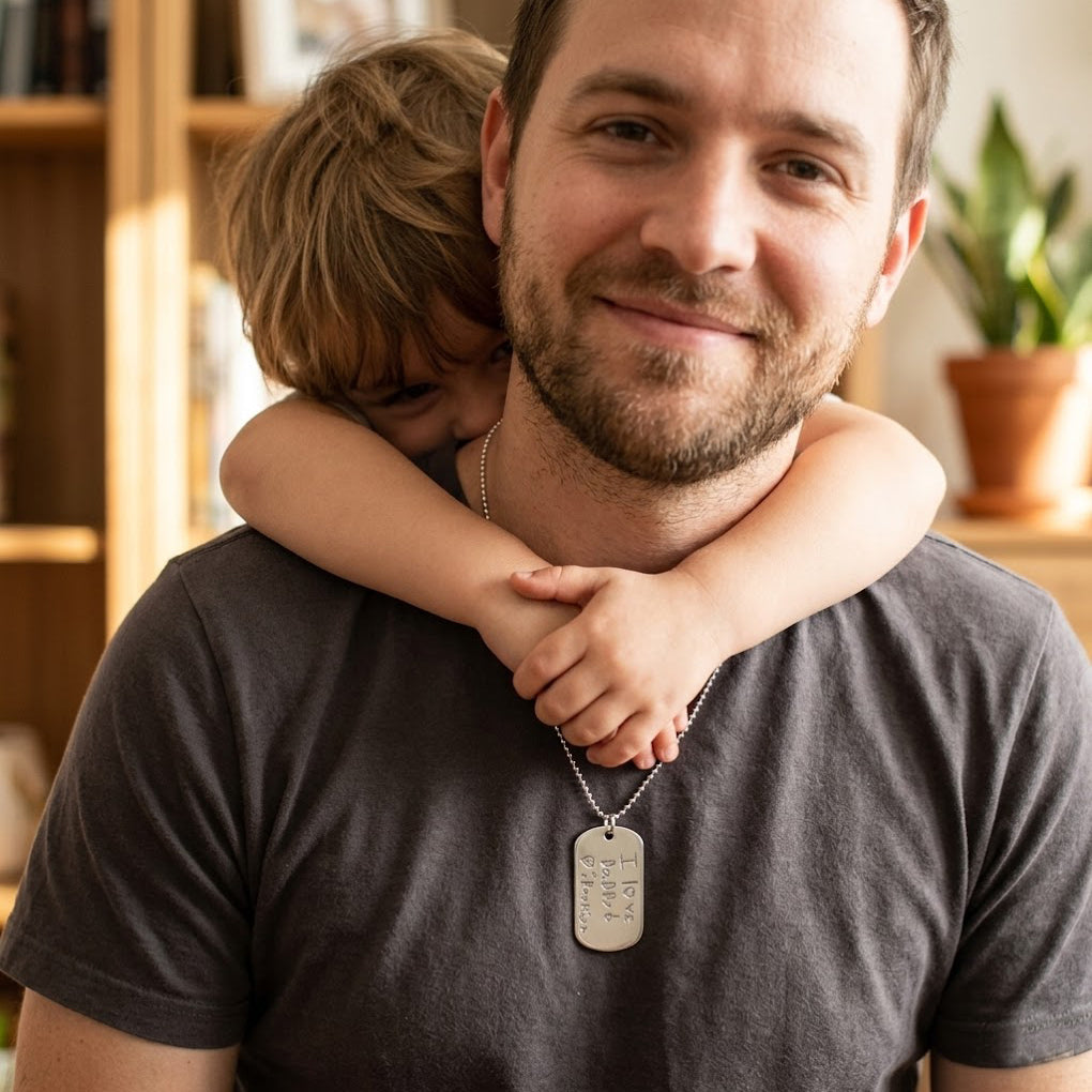 Father wearing engraved dog tag necklace with child hugging him