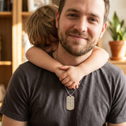 Father wearing engraved dog tag necklace with child hugging him