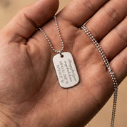Close up of custom engraved sterling silver dog tag necklace in hand