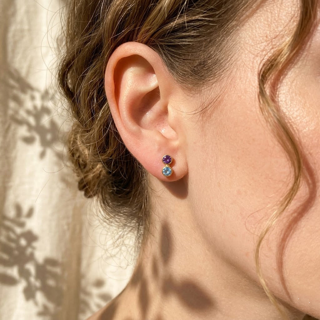 Dainty custom birthstone earrings worn on the ear with soft natural light, showing a personalized gemstone stud style for everyday wear or meaningful gifting.
