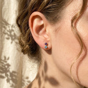Dainty custom birthstone earrings worn on the ear with soft natural light, showing a personalized gemstone stud style for everyday wear or meaningful gifting.