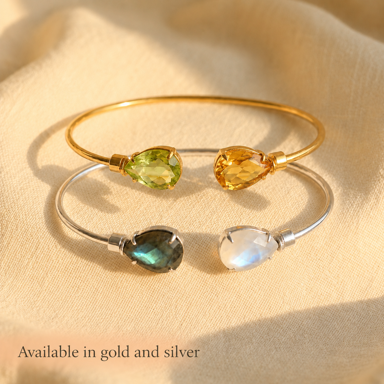 Gold and sterling silver two birthstone bangles with custom teardrop gemstones, available in gold and silver finishes.