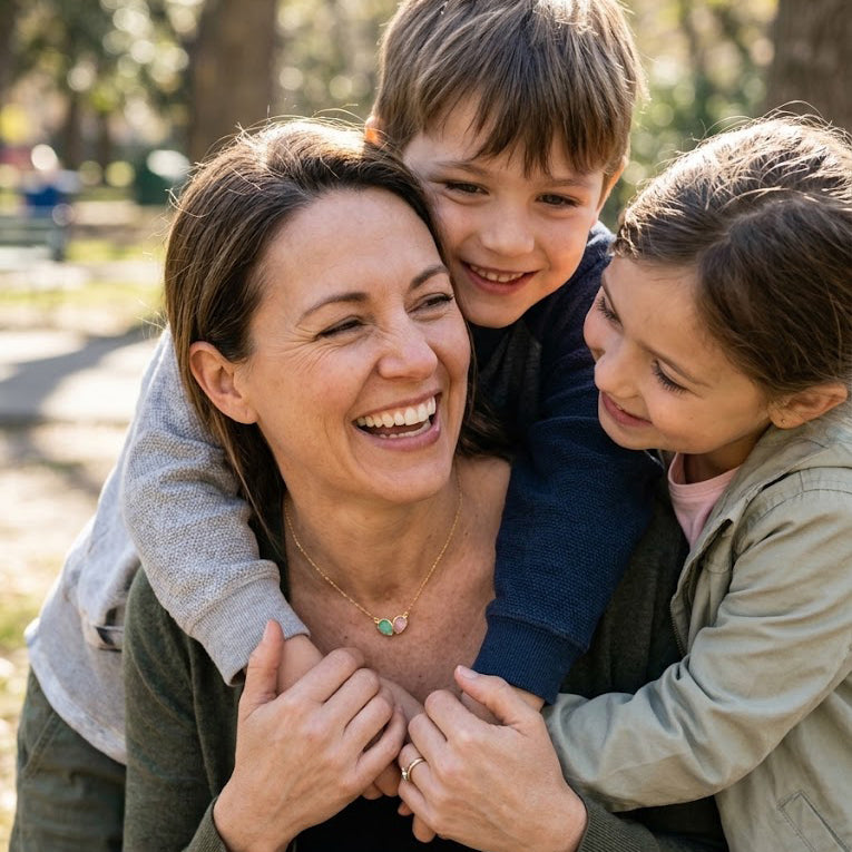 Mother with two children wearing a custom two birthstone necklace representing family members.