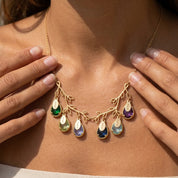 Woman wearing a personalized double-branch family tree birthstone necklace with children's engraved names.
