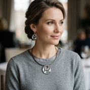 Woman wearing Sea Ice Layered Halo necklace and matching earrings with gray sweater