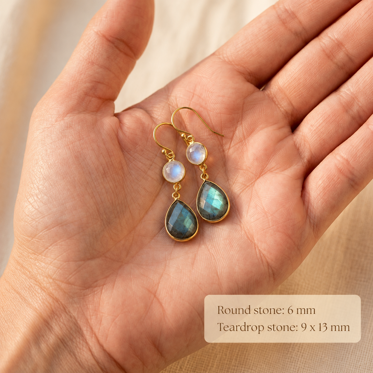 Moonstone and labradorite double drop earrings held in a woman’s hand showing gemstone scale.