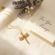 Gold dragonfly pendant necklace styled with card and soft neutral props, custom birthstone gemstone center, dainty minimalist nature jewelry look, personalized dragonfly birthstone necklace in 925 sterling silver or gold vermeil, sentimental gift for her, everyday delicate necklace