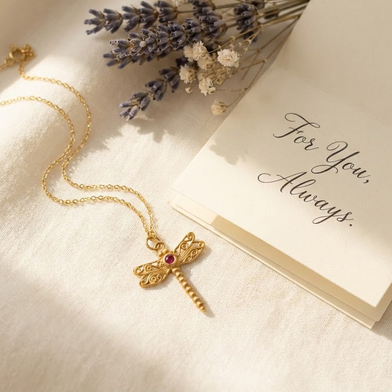 Gold dragonfly pendant necklace styled with card and soft neutral props, custom birthstone gemstone center, dainty minimalist nature jewelry look, personalized dragonfly birthstone necklace in 925 sterling silver or gold vermeil, sentimental gift for her, everyday delicate necklace