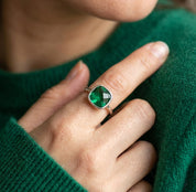 Model wearing an emerald quartz cushion ring with a green sweater, showing the bold green gemstone ring styled on hand.