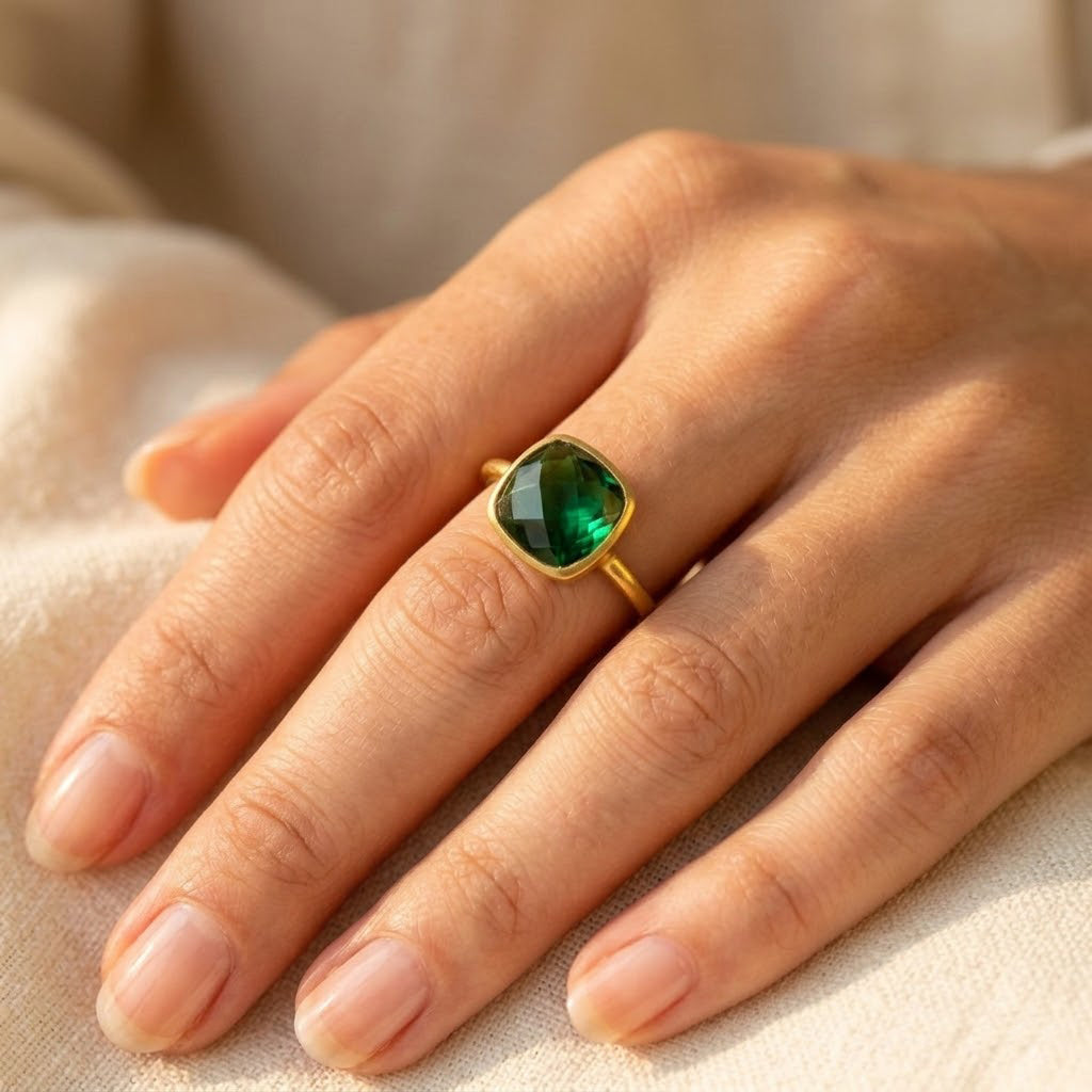 Emerald quartz cushion ring worn on hand, showing the green faceted cushion gemstone and slim gold band in natural light.