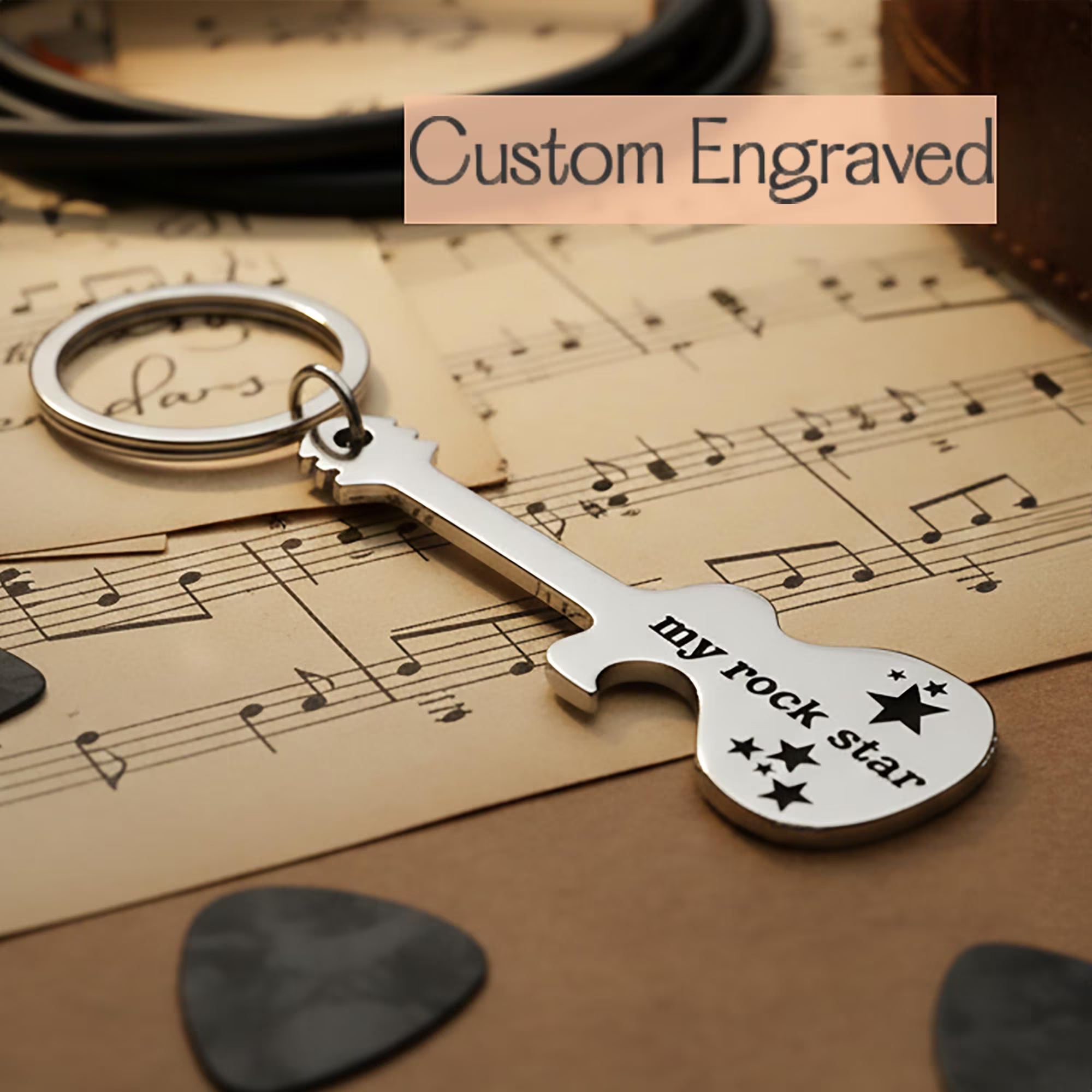 Custom engraved guitar bottle opener keychain displayed on sheet music. Music-themed personalized keychain designed as a thoughtful gift for musicians.
