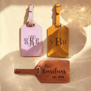 3 luggage tags in lavender, nude and cinnamon sit on a wood background. Each is engraved with a different monogram style. travel gift, personalized travel accessory, engraved leather travel label, personalized luggage identification tag, custom name baggage tag
