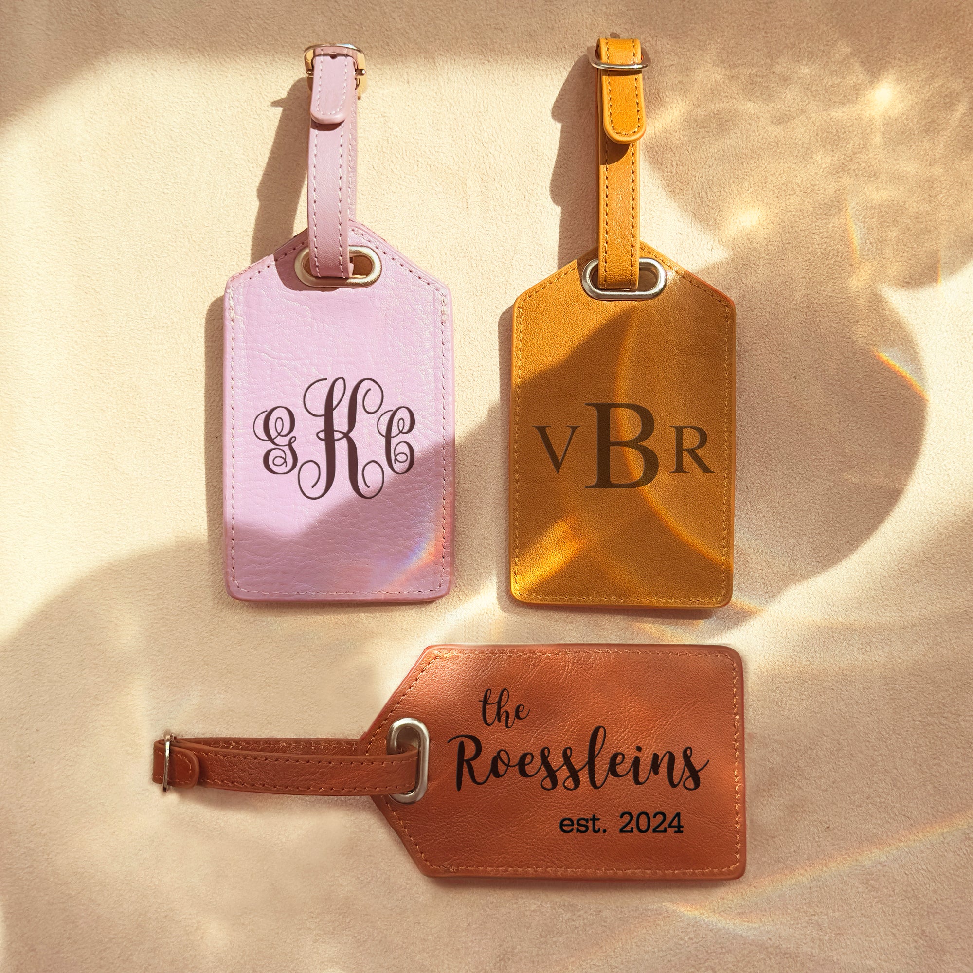 3 luggage tags in lavender, nude and cinnamon sit on a wood background. Each is engraved with a different monogram style. travel gift, personalized travel accessory, engraved leather travel label, personalized luggage identification tag, custom name baggage tag