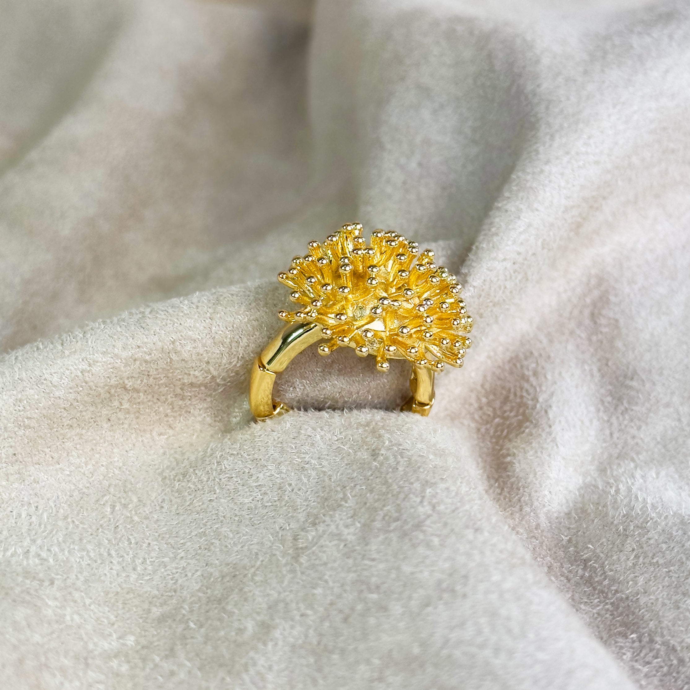 A gold zinc alloy adjustable dandelion burst statement ring sits on a velvet background. Adjustable gold ring, flower ring, floral ring, Nature inspired dandelion ring, dandelion puff jewelry, size 6, size 7, size 8, stretchy adjustable ring for women, Mother's Day gift for her, birthday gift for women