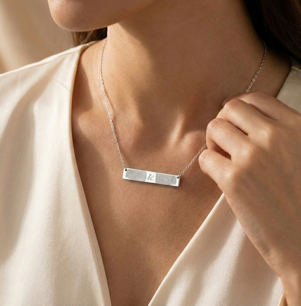 Woman wearing a personalized sterling silver fingerprint bar necklace, minimalist horizontal bar pendant engraved with a custom fingerprint, delicate everyday necklace styled on model, meaningful memorial and sentimental jewelry gift