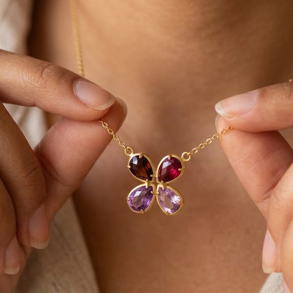 Custom four birthstone necklace with four colorful faceted teardrop gemstones in yellow gold representing loved ones.


