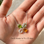 Hand holding a four birthstone necklace showing the faceted teardrop gemstone size and colorful family combination.
