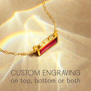Garnet bar necklace with custom engraving displayed on soft fabric, highlighting baguette cut gemstone, deep red tones, and personalized engraving options for meaningful jewelry