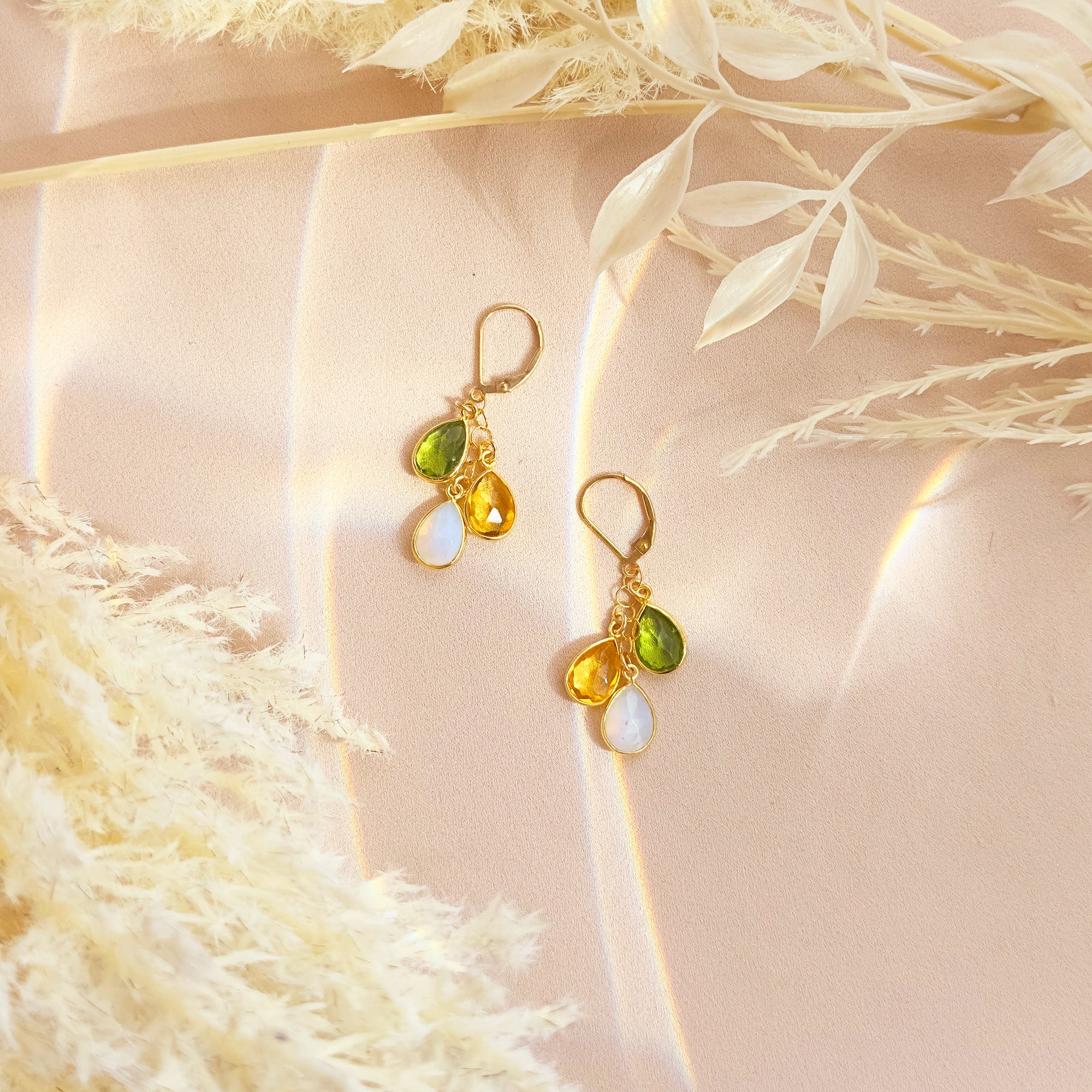 Elegant custom gold birthstone earrings featuring three teardrop gemstones in green peridot, yellow citrine, and iridescent moonstone. These personalized family earrings are handcrafted to symbolize children’s or loved ones’ birth months, creating a timeless keepsake for moms, grandmothers, and wives. Perfect for Mother’s Day, birthdays, or anniversaries, this dainty gemstone jewelry piece combines elegance, sentiment, and everyday wearability.