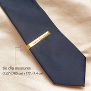 Gold engraved tie bar on black tie, showcasing slim design and elegant personalization, perfect gift for groom, groomsmen, or anniversary.