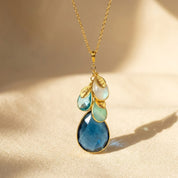 Personalized birthstone necklace for mom or grandma featuring a large teardrop birthstone with smaller family birthstone charms on a gold chain, a meaningful custom jewelry gift.