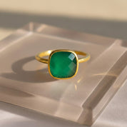 Green onyx cushion cut bezel set ring displayed on neutral background, featuring a faceted green onyx gemstone in a smooth gold bezel. Minimalist May birthstone ring designed for everyday wear, stacking, or gifting, available in sterling silver or gold vermeil.