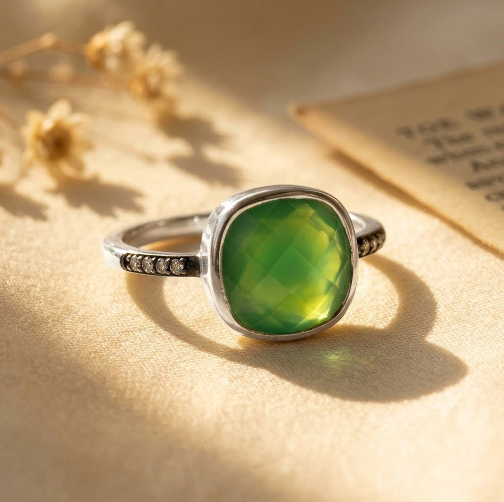 Sterling silver cushion-cut green onyx ring with clear pavé stones on warm beige fabric.