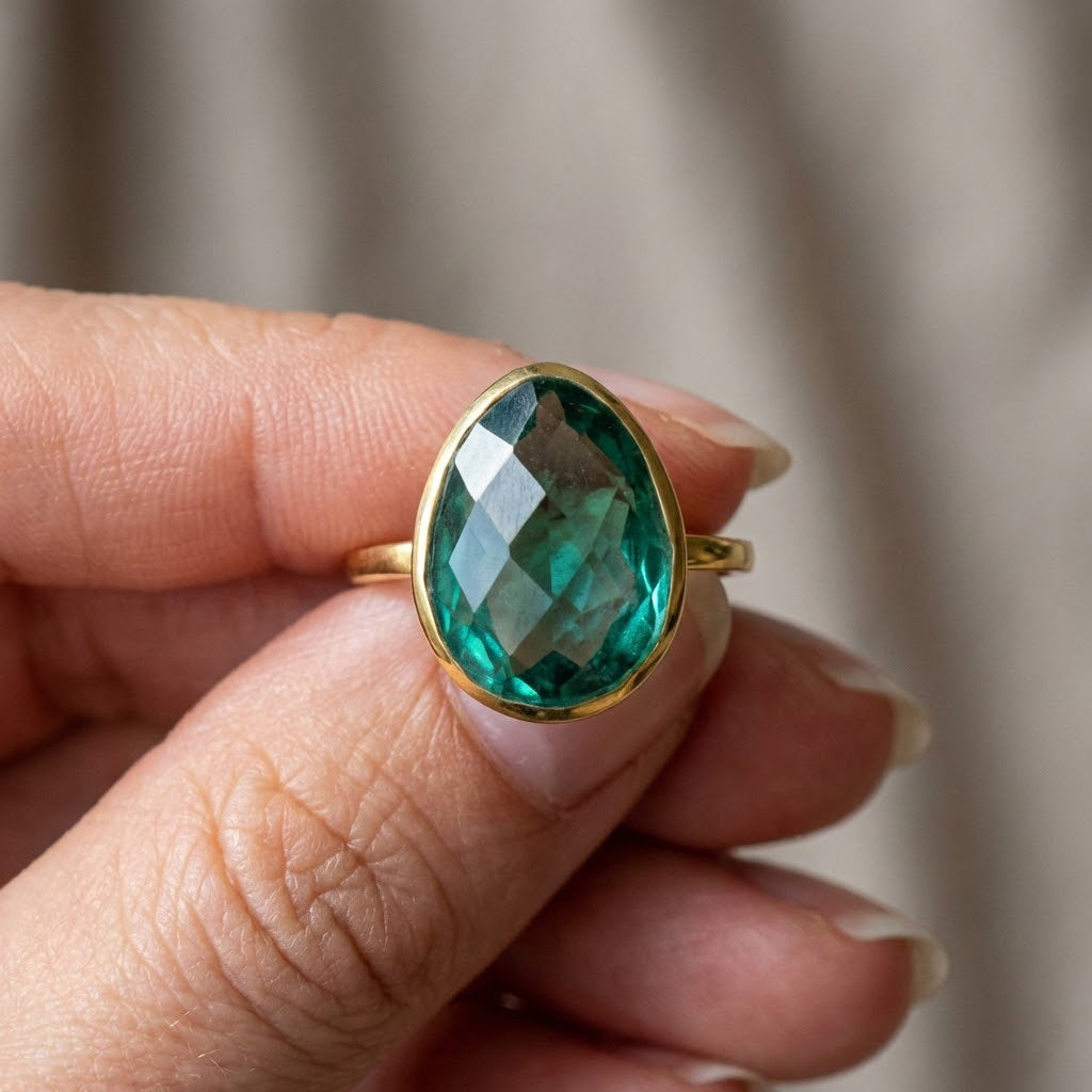 Close-up of faceted green tourmaline oval gemstone in bezel setting, vibrant deep green October birthstone ring in 14k gold, modern handcrafted statement jewelry