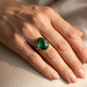 Green tourmaline oval cocktail ring styled on hand, bold minimalist October birthstone ring in gold setting, modern gemstone jewelry for women